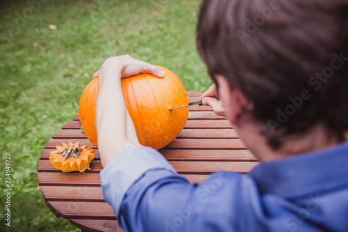 Happy halloween. Man carving big pumpkin Jack O Lanterns for Halloween outside. Close-up photo