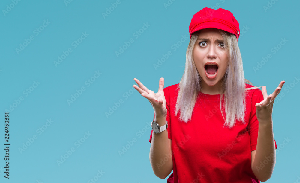 Young blonde woman wearing red hat over isolated background crazy and mad shouting and yelling with aggressive expression and arms raised. Frustration concept. Young blonde woman wearing red hat over isolated background crazy and mad shouting and yelling with aggressive expression and arms raised. Frustration concept.