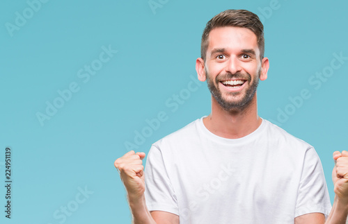 Young handsome man over isolated background celebrating surprised and amazed for success with arms raised and open eyes. Winner concept. © Krakenimages.com