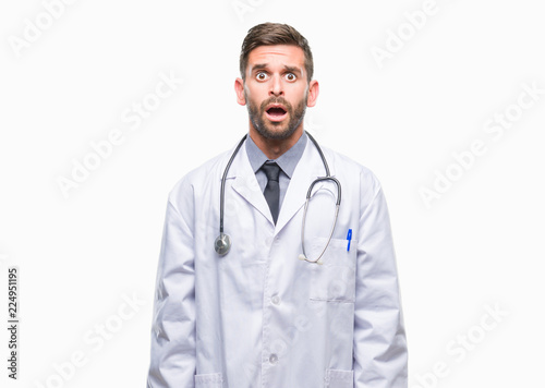 Young handsome doctor man over isolated background afraid and shocked with surprise expression, fear and excited face.