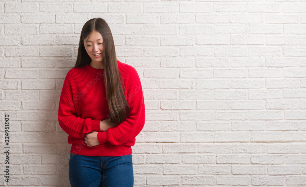 Young Chinese woman over brick wall with hand on stomach because nausea, painful disease feeling unwell. Ache concept. Young Chinese woman over brick wall with hand on stomach because nausea, painful disease feeling unwell. Ache concept.