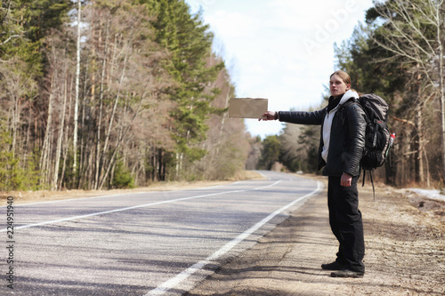 A young man is hitchhiking around the country. The man is trying