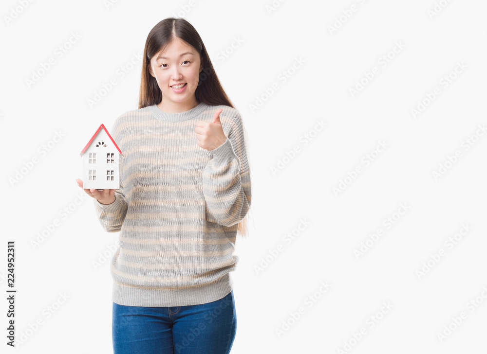 Young Chinese real state agent woman over isolated background holding house happy with big smile doing ok sign, thumb up with fingers, excellent sign Young Chinese real state agent woman over isolated background holding house happy with big smile doing ok sign, thumb up with fingers, excellent sign