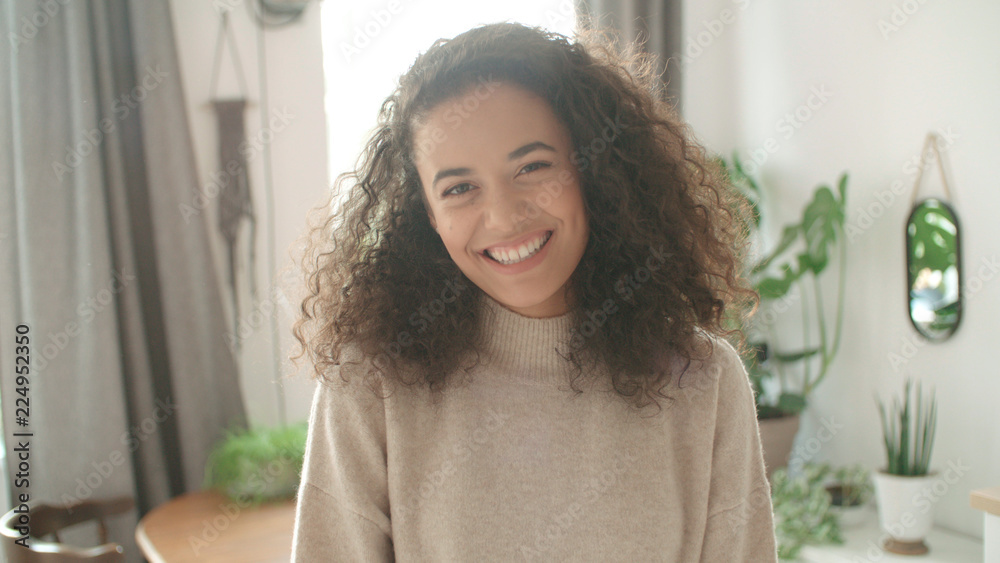 Portrait of a beautiful young woman smiling at the camera in a kitchen.