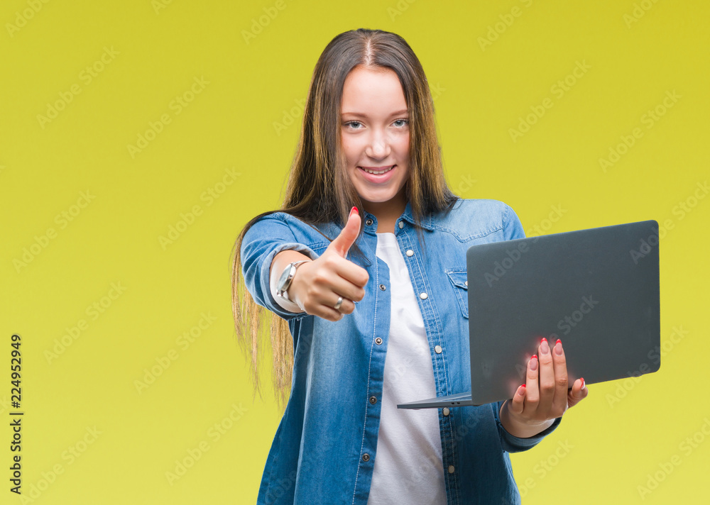 Young caucasian woman using laptop over isolated background happy with big smile doing ok sign, thumb up with fingers, excellent sign Young caucasian woman using laptop over isolated background happy with big smile doing ok sign, thumb up with fingers, excellent sign