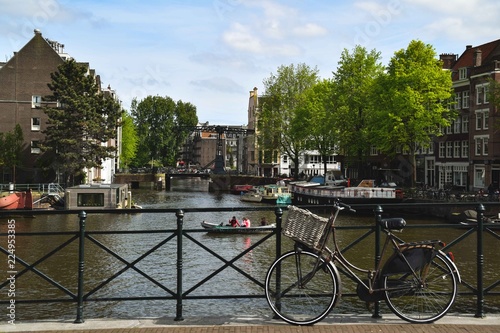 Bicycle on a bridge with canal and typicals house in the background - Amsterdam, Netherlands