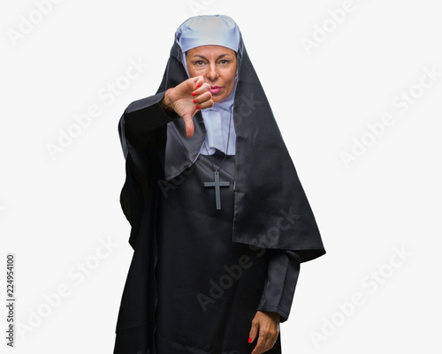 Middle age senior christian catholic nun woman over isolated background looking unhappy and angry showing rejection and negative with thumbs down gesture. Bad expression.