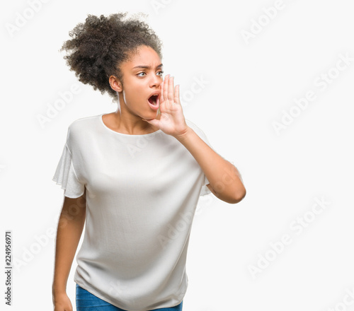 Young afro american woman over isolated background shouting and screaming loud to side with hand on mouth. Communication concept.