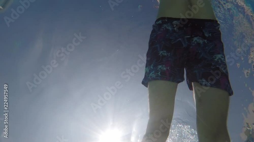 A man swims over the camera in the pool, underwater shooting, slow-motion
