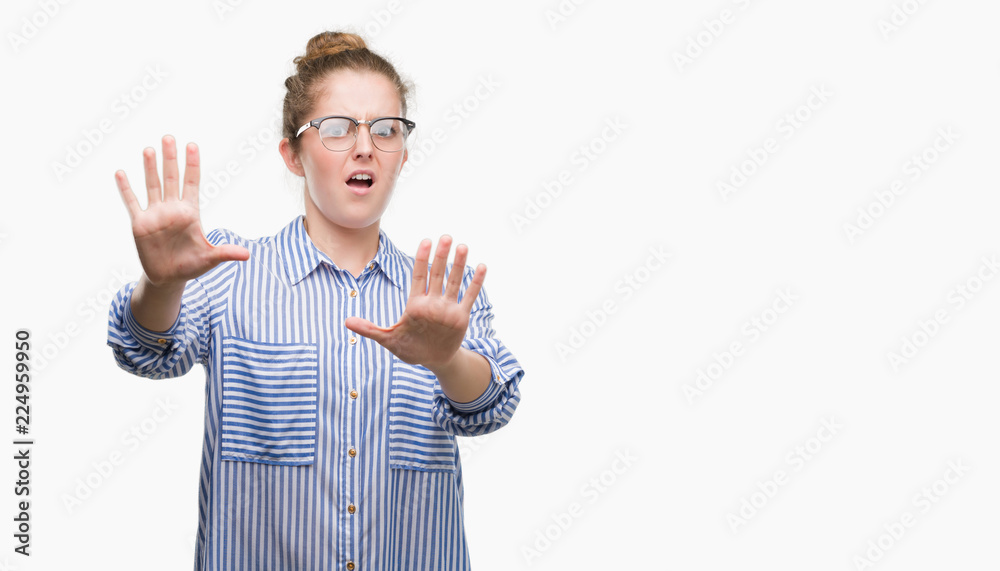 Young blonde business woman afraid and terrified with fear expression stop gesture with hands, shouting in shock. Panic concept. Young blonde business woman afraid and terrified with fear expression stop gesture with hands, shouting in shock. Panic concept.