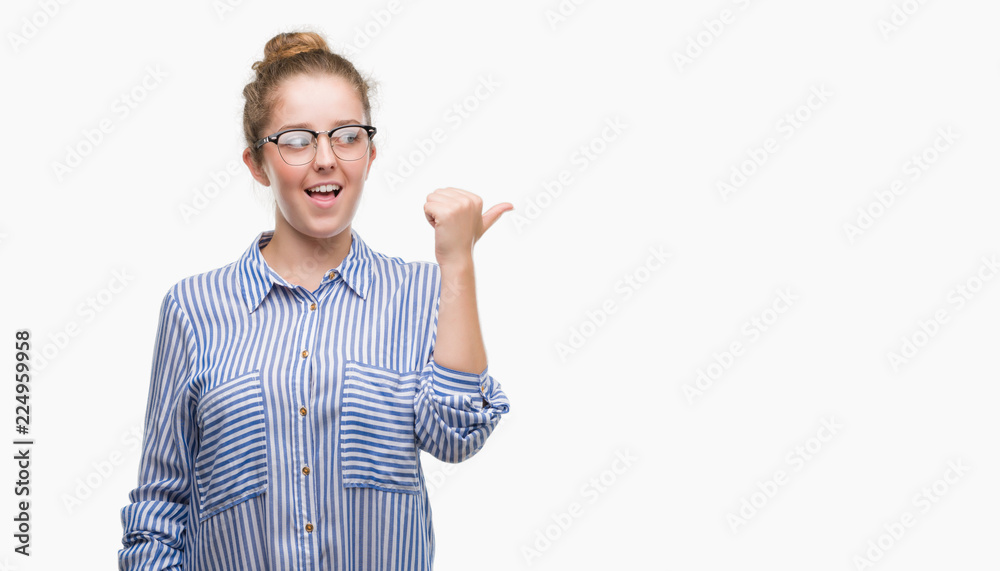 Young blonde business woman smiling with happy face looking and pointing to the side with thumb up. Young blonde business woman smiling with happy face looking and pointing to the side with thumb up.