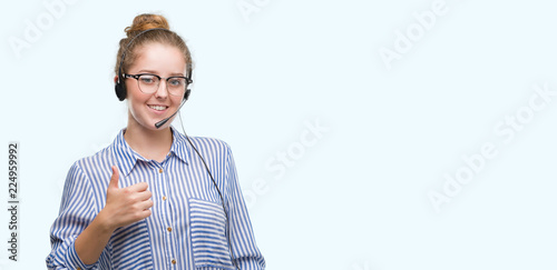 Young blonde call center operator woman happy with big smile doing ok sign, thumb up with fingers, excellent sign