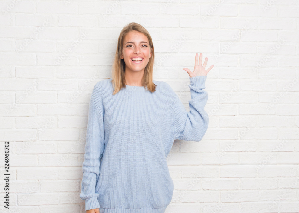 Beautiful young woman over white brick wall showing and pointing up with fingers number five while smiling confident and happy. Beautiful young woman over white brick wall showing and pointing up with fingers number five while smiling confident and happy.