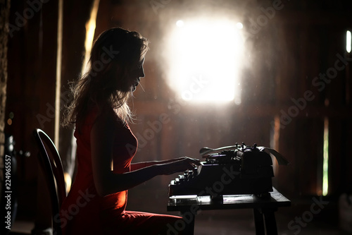 A girl in retro style prints on an old typewriter