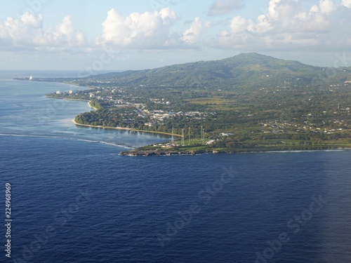 Fototapeta Naklejka Na Ścianę i Meble -  Aerial view of Saipan western coast from a distance, with the deep blue waters of the Saipan-Tinian channel in between