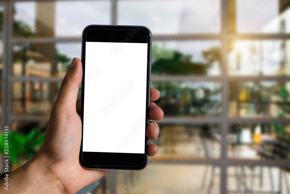 Hand holding white mobile phone with blank white screen  at the corner of the gym.