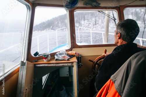Captain of the ship at the wheel, in the cockpit of the old boat