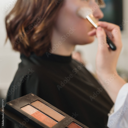 Closeup of professionsl makeup artist applying eyeshadows with brush photo