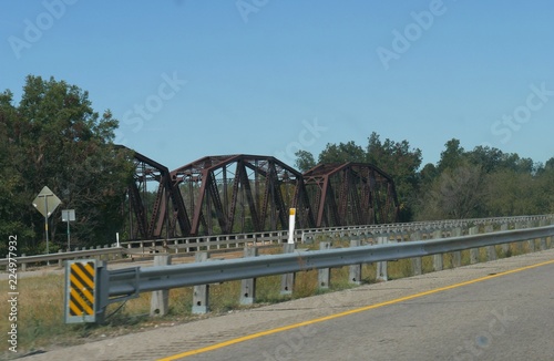 Old covered rusty bridge by the side of a new highway