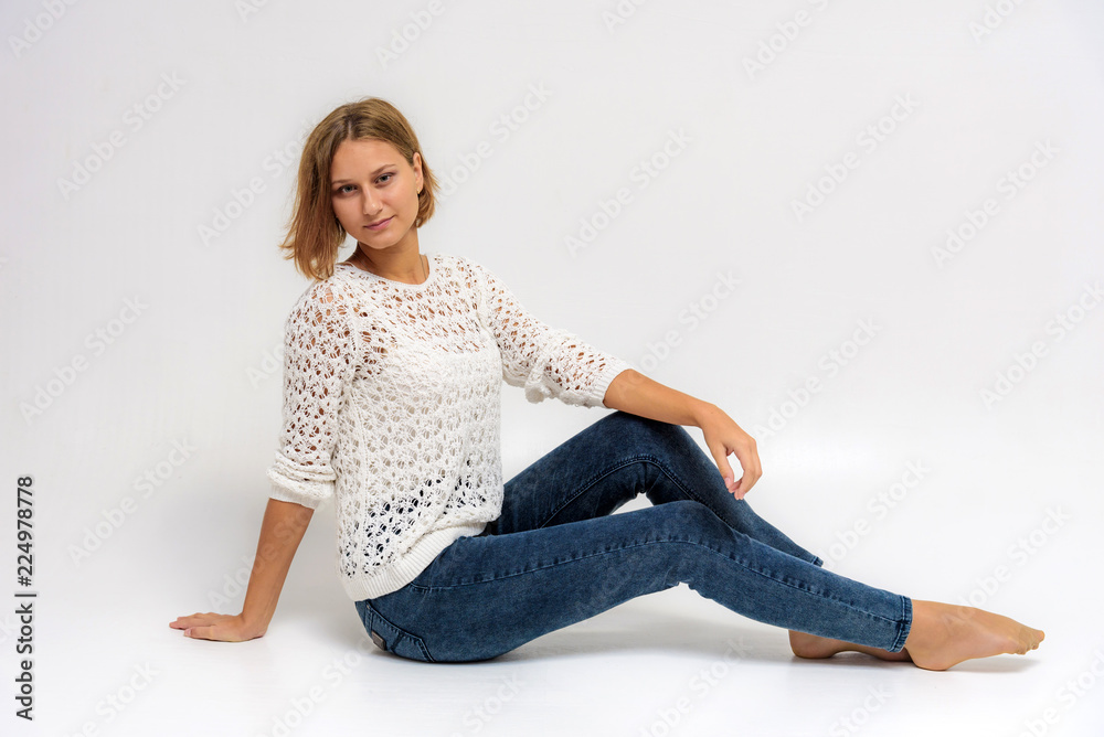 portrait of a young beautiful girl on a white background sitting on the floor.