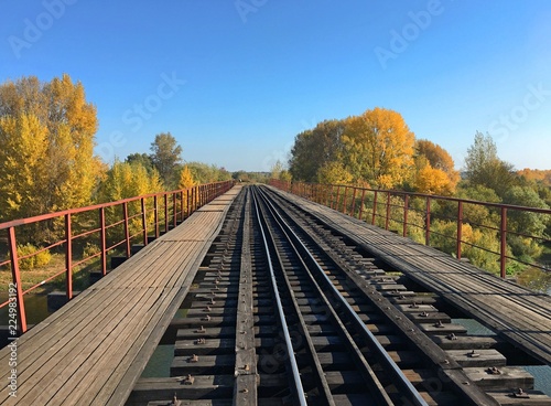 Railway bridge over the river under the blue sky in autumn