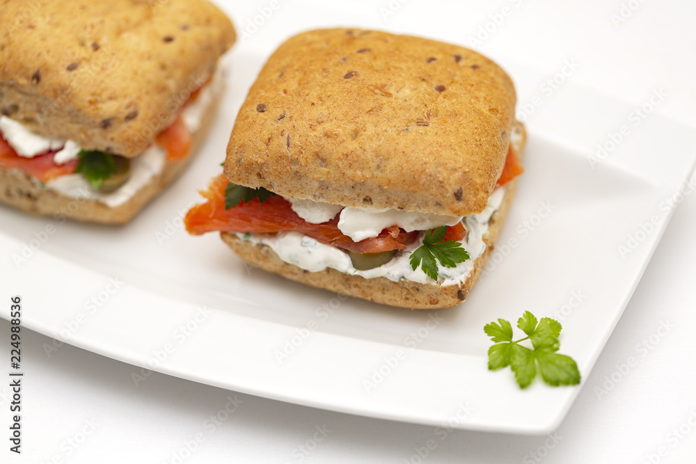 Sandwich with salmon, cheese and cereal bread on white background. Close up. Sandwich with salmon, cheese and cereal bread on white background. Close up.