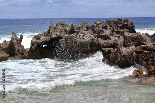 Sharp rocks and corals protecting a swimming cove from the direct waves from the ocean in a tropical island