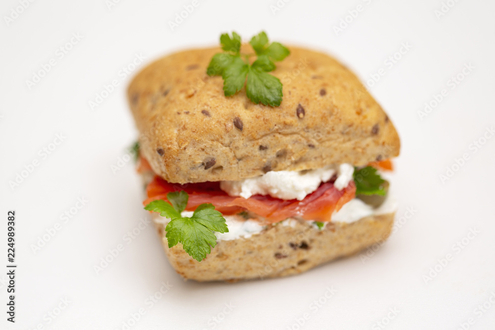 Sandwich with salmon, cheese and cereal bread on white background. Close up. Sandwich with salmon, cheese and cereal bread on white background. Close up.