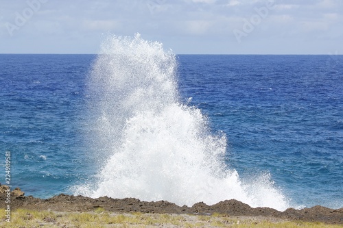 Mesmerizing splashing waves crash against the rocky shoreline of a coast in the tropical area