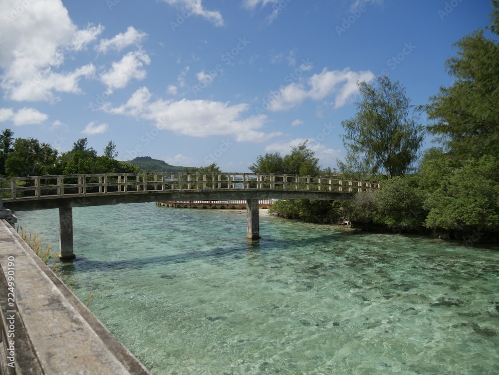 Concrete bridge over green clear waters of an abandoned waterpark on Rota, Northern Mariana Islands