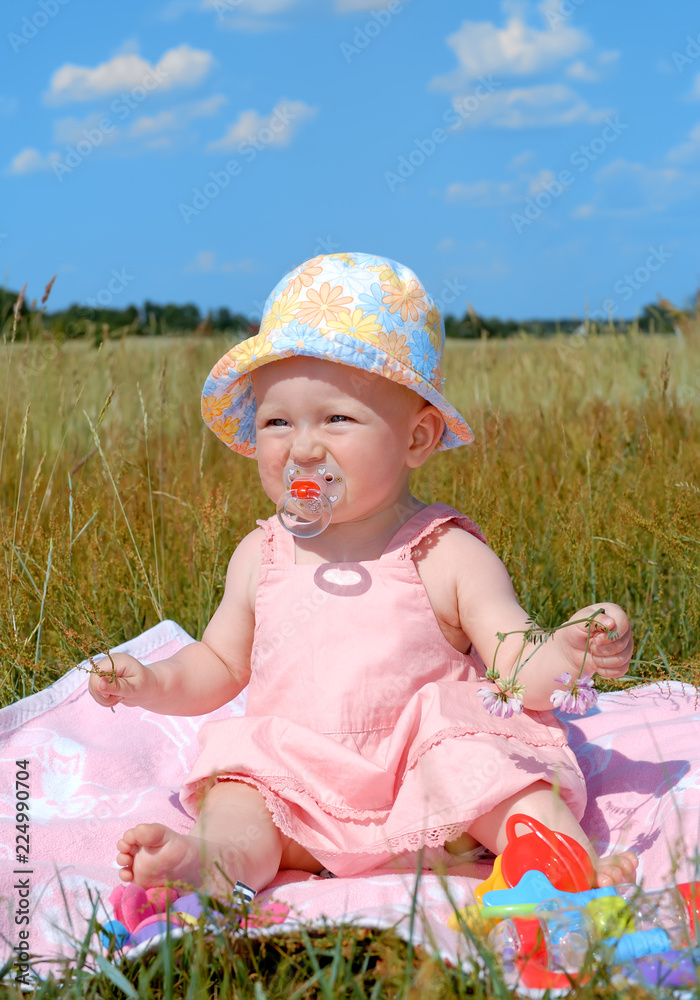 Little girl in a hat sitting on green field Little girl in a hat sitting on green field