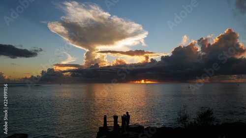 Beautiful sunset with the silhouette of a man standing by the latte stones in a tropical island photo