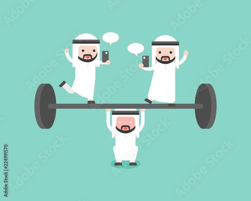 Arab businessman try to weigh lifting barbell with another playing cellphone on barbell
