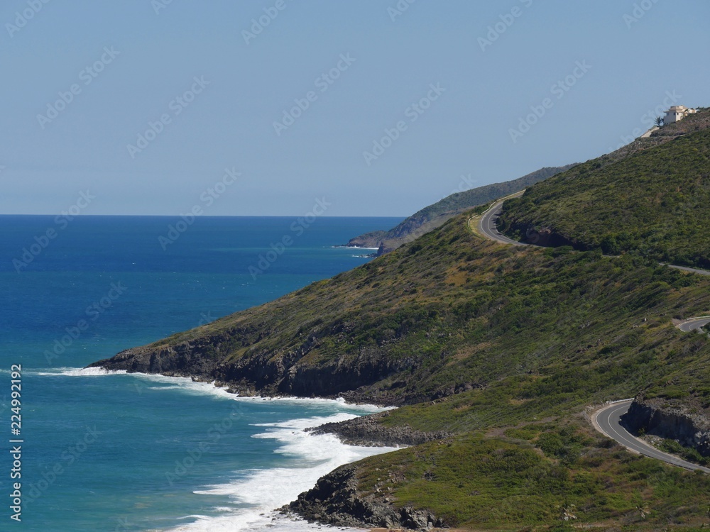 Scenic coastal view of pristine blue waters and winding paved roads in the mountainside at the Frigate Bay, St. Kitts, West Indies 