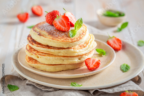 Yummy american pancakes with fresh strawberries and sugar