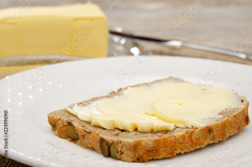 Eine Scheibe Butterbrot und ganze Butter im Hintergrund