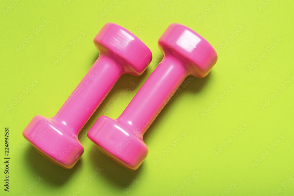 Pair of pink dumbbell on green color Pair of pink dumbbell on green color