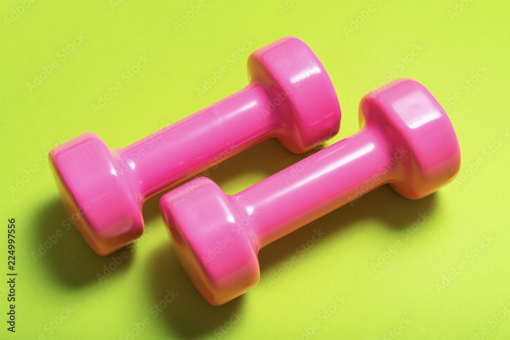 Pair of pink dumbbell on green color Pair of pink dumbbell on green color