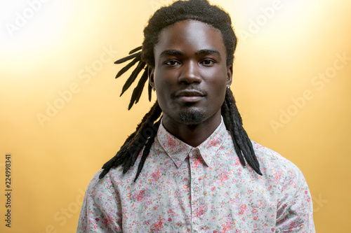 Foto young handsome afro american man with dreadlocks isolated on yellow background