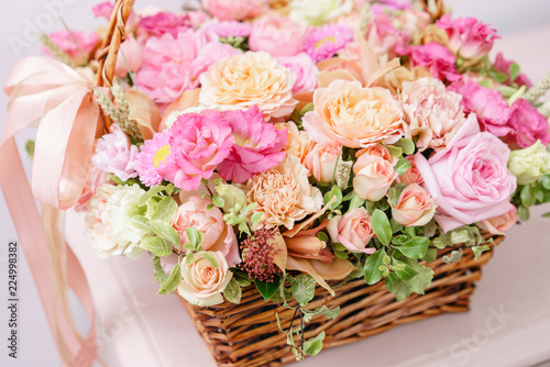 flowers arrangement with various of colors in wicker basket on pink table. beautiful spring bouquet. bright room  white wall. copy space