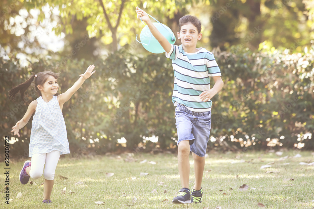 Obraz premium Kids playing with a balloon in the park. Children having fun outdoors concept