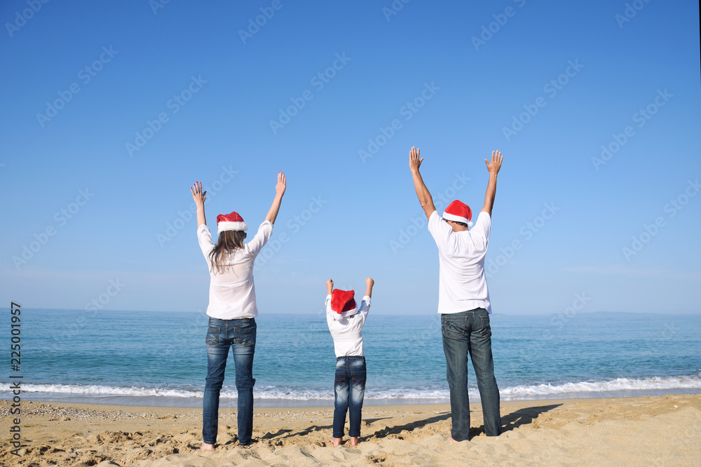 Happy family in Christmas Hats having fun on sandy beach. New Year holidays concept Happy family in Christmas Hats having fun on sandy beach. New Year holidays concept
