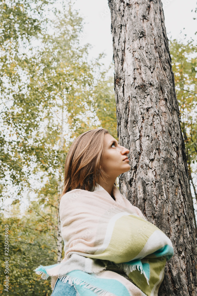 Lifestyle portrait of young woman wrapped herself in scarf in forest or park, selective focus Lifestyle portrait of young woman wrapped herself in scarf in forest or park, selective focus
