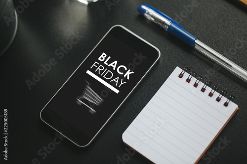 Black Friday marketing design in a mobile phone screen over a black business table.