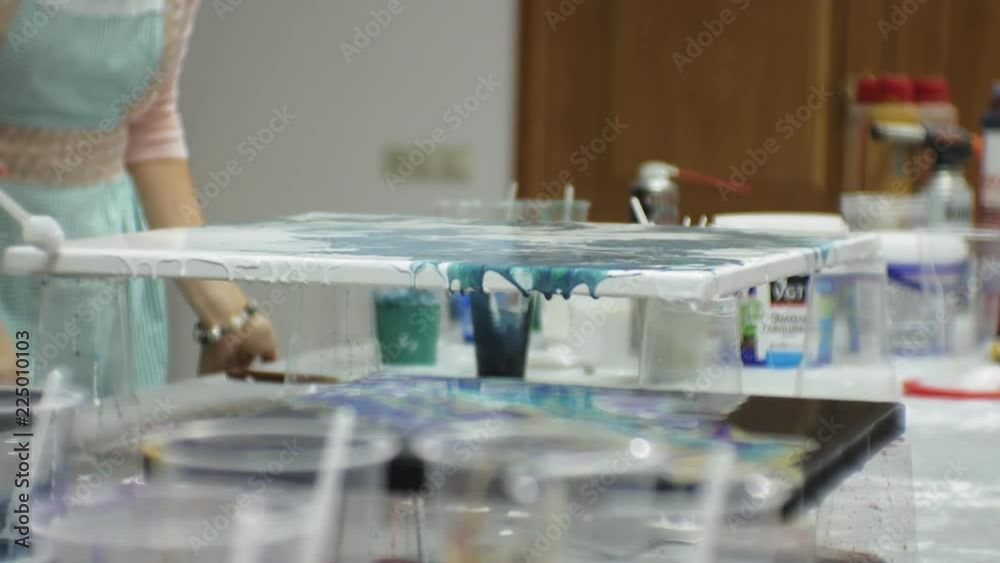 women in an art studio mix paints and draw on canvas in fluid art technique women in an art studio mix paints and draw on canvas in fluid art technique