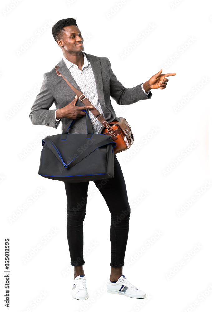 Obraz premium Full body of African american business man traveling with suitcases pointing finger to the side and presenting a product while smiling on white background
