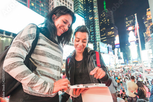 Girls in New York at night looking at smart phone