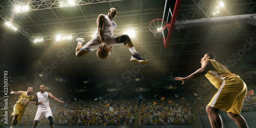 Basketball players on big professional arena during the game. Basketball player makes slum dunk. Bottom view © Alex