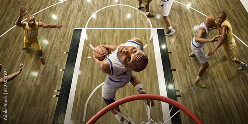 Basketball players on big professional arena during the game. Basketball player makes slum dunk. Top view through the basketball hoop photo