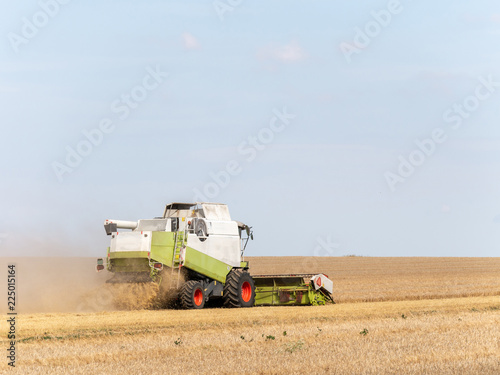 Combine harvesters on the field. Combine harvest on grain field. Summer harvest and blue sky. Harvesting on grain field. Harvests wheat in the fields in summer.